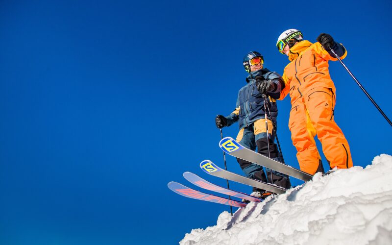 Two skiers smiling at the top of a piste