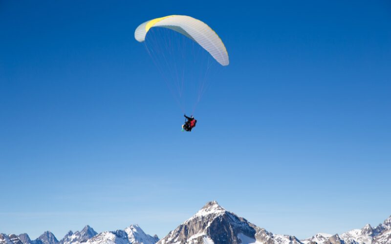 A paraglider flying over the mountains of La Plagne