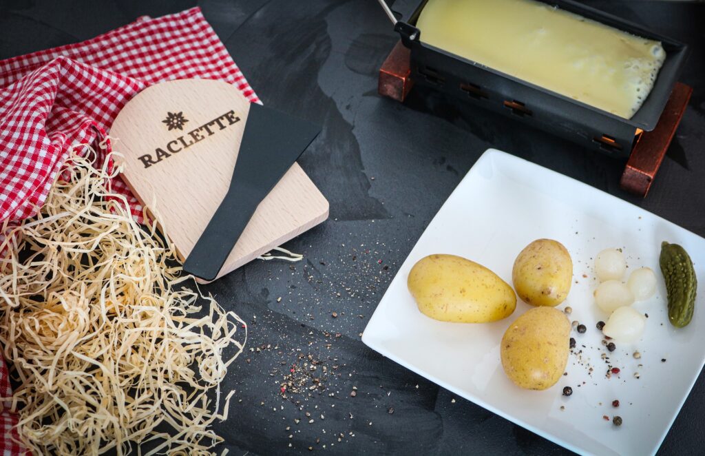 Raclette: gooey melted cheese with potatoes and pickled pearl onions on a plate.