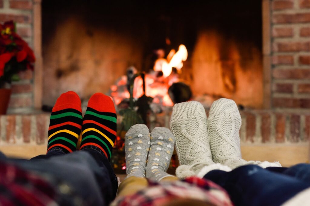 Three pairs of socked feet warming by the fire.